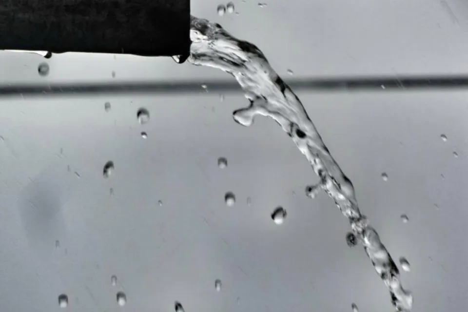 Water pouring out of the end of a black pipe
